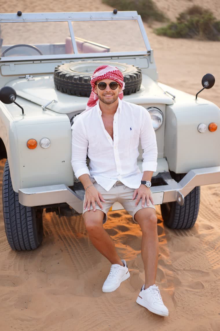 Ben mit Kufiya auf der Stoßstange eines alten Land Rover in der Wüste