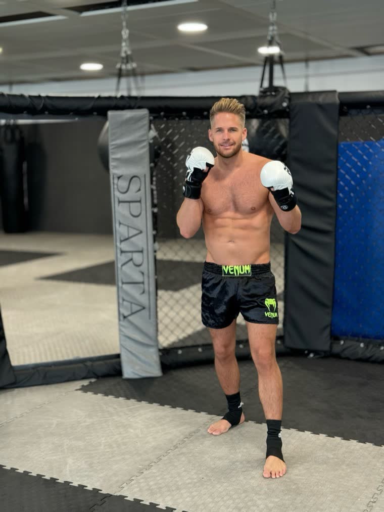 Ben mit MMA-Handschuhen in Deckung im Käfig